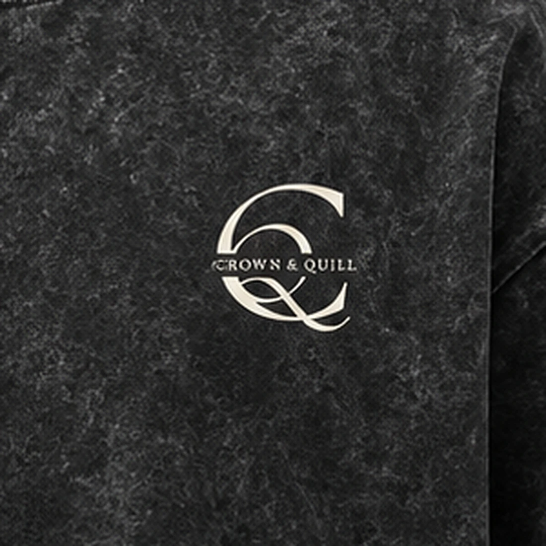 Crown and Quill chest monogram close-up in cream on acid-wash black